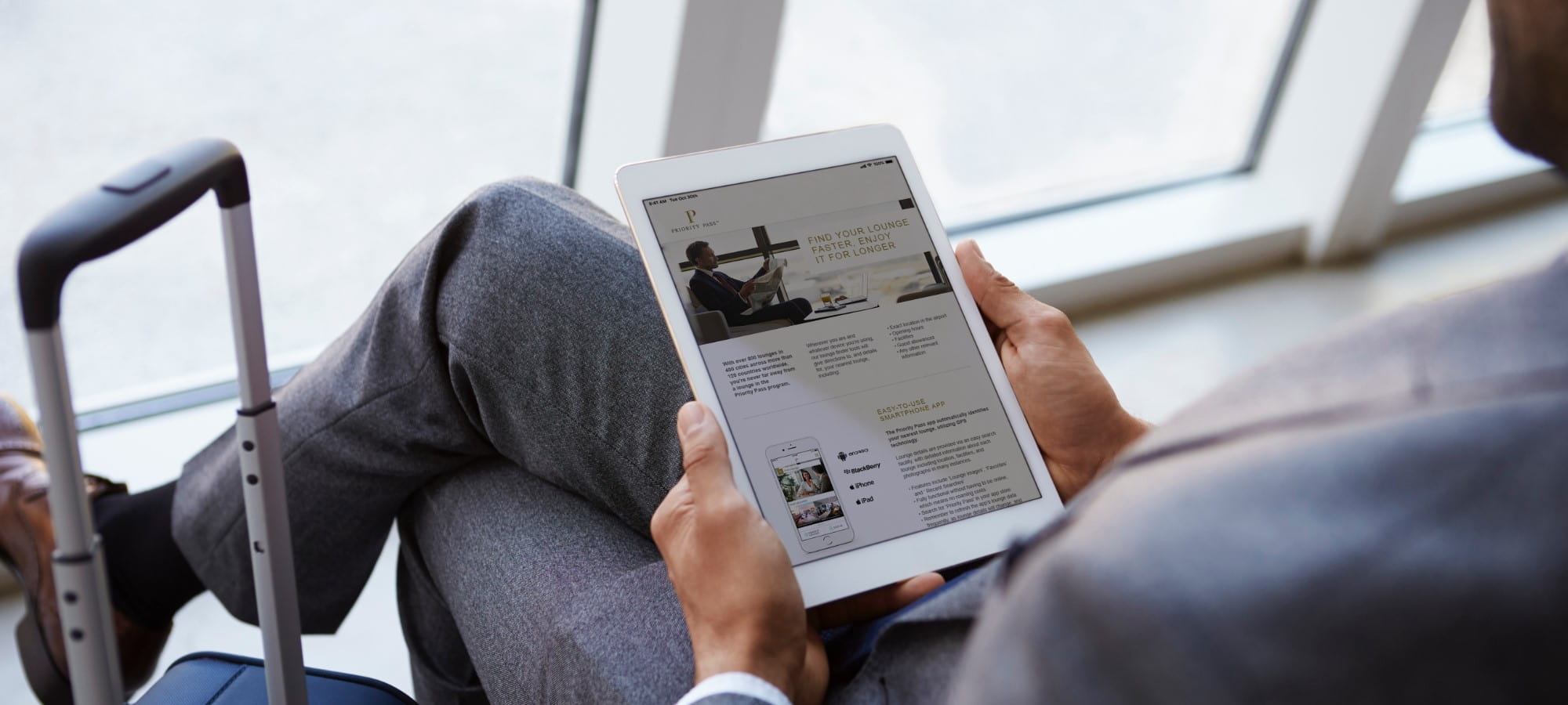 Man reading priority pass website on tablet in airport lounge